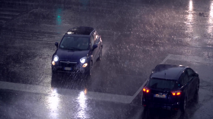 Milan, Italy. Night city in rainy weather. Cars passing on the wet asphalt of city streets. Traffic lights at night. Reflection in puddles on the ground. Crossroads at night. food delivery bike. 