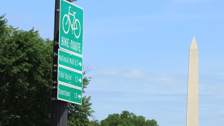 A Washington, D.C bike route sign near the Lincoln Memorial with the Washington Monument in the background.