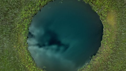 Lake Bezdonnoe in Moskovskaya oblast' shot from drone. Drone aerial shot zoom out of green trees in Moskovskaya oblast with a view over a round circle lake bezdonnoe, botomless lake in Russia