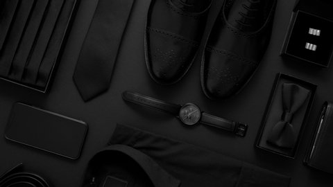 Elegant man clothes concept. Set of black wardobe and accessories for official party or evening meeting. Placed on black backgound. With shirt, shoes, watch, bow, tie. Top view. Flat lay.