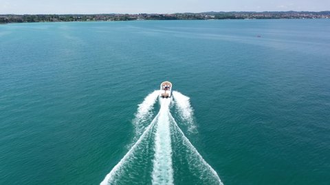 A high-speed boat moves at high speed along the coastline of blue water