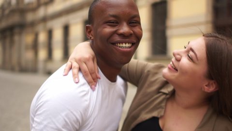 Black man and white woman. Mixed race couple hugging on a city street. Closeup of young couple in love. The meeting of two friends students