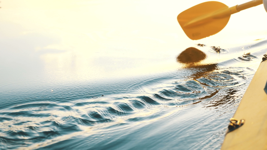 Oar paddles on calm water against the background of sunset rays, outdoor activities on a kayak, water sports | Shutterstock HD Video #1054614050