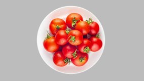 Video with view from top of red ripe tomatoes on rotated white plate. Looped motion with alpha matte