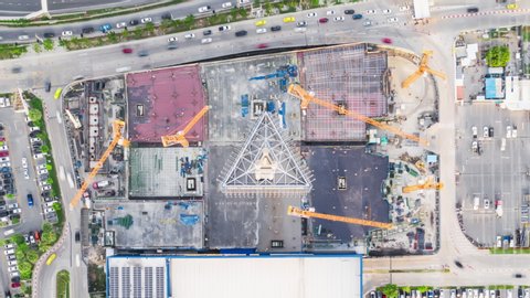 4K time-lapse of under construction site, crane, parking lot, car traffic transportation in Asian city. Drone aerial top view. Industrial business or civil engineering technology concept. Zoom out