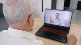 Senior man having videoconferencing with online male doctor. Remote patient consulting video call in conference virtual webcam chat app. Over shoulder laptop screen view.