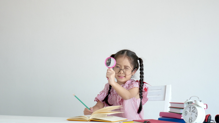 Little girl stand and action of observing around in front of clock and stack of book. Concept of girl play as teacher and happy, fun with learn to get new knowledge.