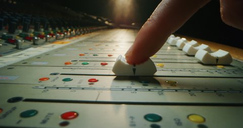Macro slide shot of a sound producer hand is using a music mixer with editing tools in a professional recording studio.
