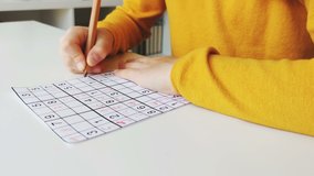 Video of close-up children's hands solving sudoku puzzle with a pencil as a hobby at home