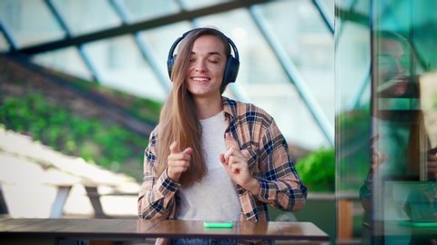 Happy joyful fun smiling woman music lover with wireless headphones listening favorite song, dancing and enjoying music in a cafe