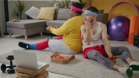 Multi-race funny chubby retro guys in sportswear doing fun wrong biceps exercises and enjoying fast food pizza. Concept of sports, fun, entertainment.