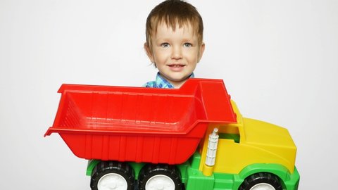 A beautiful little boy rejoices to a big toy truck in his hands