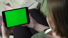 Closeup of woman with dark pants having green screen video call via tablet talking to friends and family.