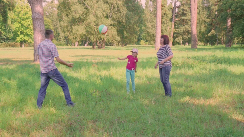 Family volleyball in nature. Dad and daughter play volleyball. Granddaughter and grandmother play ball. Family rest in the park in nature. Father and daughter have fun. Grandmother and granddaughter