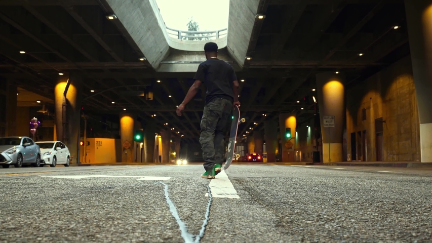 Young athletic black male skateboarder, confident handsome man, in urban garage street in Los Angeles. Concept of urban healthy active lifestyle, american hipster millennial in NYC.