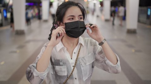 Asian woman take off black mask, stand at center of the frame, metro train station, covid girl inside subway station, New normal lifestyle, self protection, public transportation, pedestrian walk