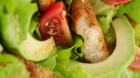 chicken salad with avocado, tomatoes, lettuce, sesame seeds rotating. Healthy salad with chicken. vertical video