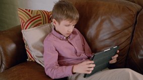 casual relaxed child boy surfing searching internet browsing online videos Spbas. kid on quarantine sitting on sofa and using technology. concept childhood, leisure
