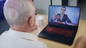 Senior man having video conference on his laptop. Online webinar or online training for pensioners. Communication remotely using a computer
