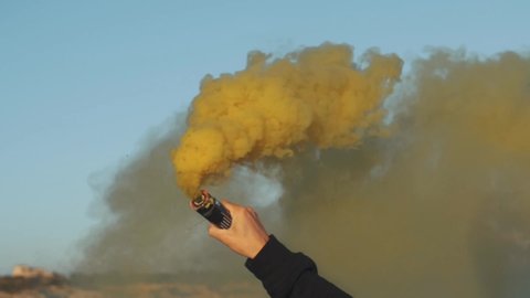 Man holds a yellow smoke bomb in his hand - Slow Motion Footage