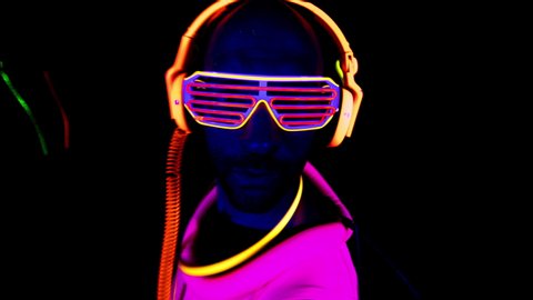 Person wearing bright coloured clothing and headphones dancing in nightclub