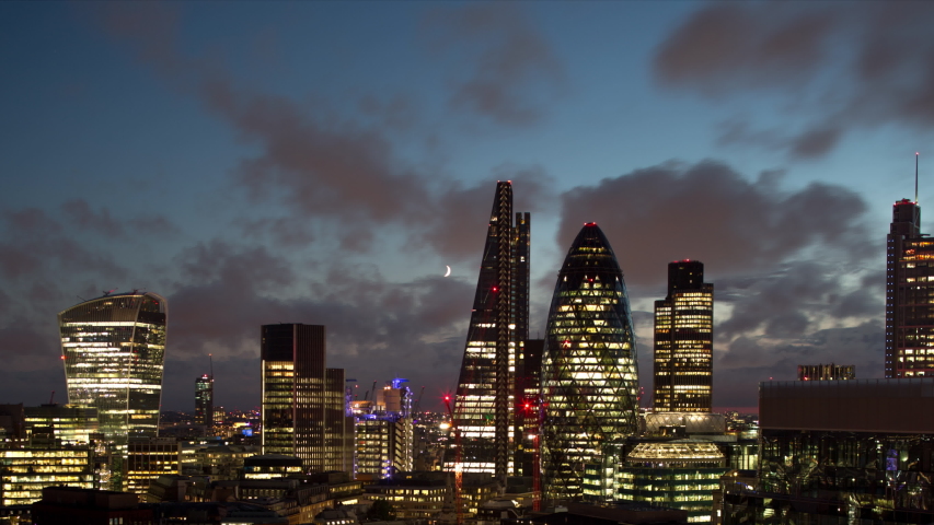 Back and forth Day to night time lapse video of clouds moving in sky above buildings over London, England