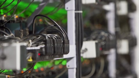 Data center diagnostics technician installs ASIC bitcoin miner on rack, connects ethernet cable. Mining equipment server service. Administrator repairs farm cryptocurrency computing cluster network.