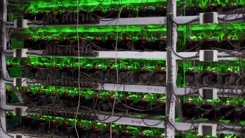 Cryptocurrency mining equipment on large farm. ASIC miners on stand racks mine bitcoin in server room. Blockchain techology application specific integrated circuit. Tripod panorama.