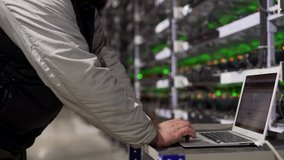Data center diagnostics technician works and types on laptop. Mining equipment service in server room. Administrator repairs computing cluster with network hardware lights on background. Slider shot. - Powered by Shutterstock - Get 15% off with code: PIKWIZARD15