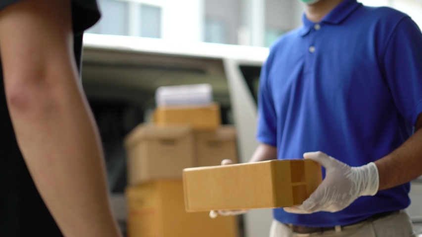 Corona Virus Concept. Asian blue delivery man wearing protection mask and medical rubber gloves send a package to customer on before deliver cargo. 4k resolution and slow motion shot. Royalty-Free Stock Footage #1054682633