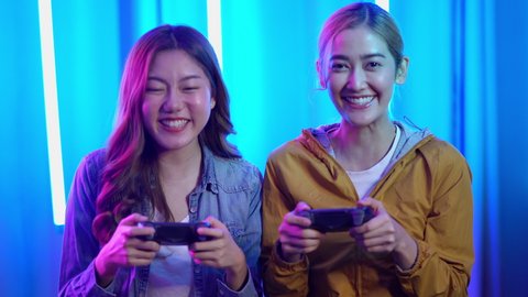 Excited funny young adult couple woman gamers holding controllers playing video game friends winning videogame having fun together celebrating victory at home