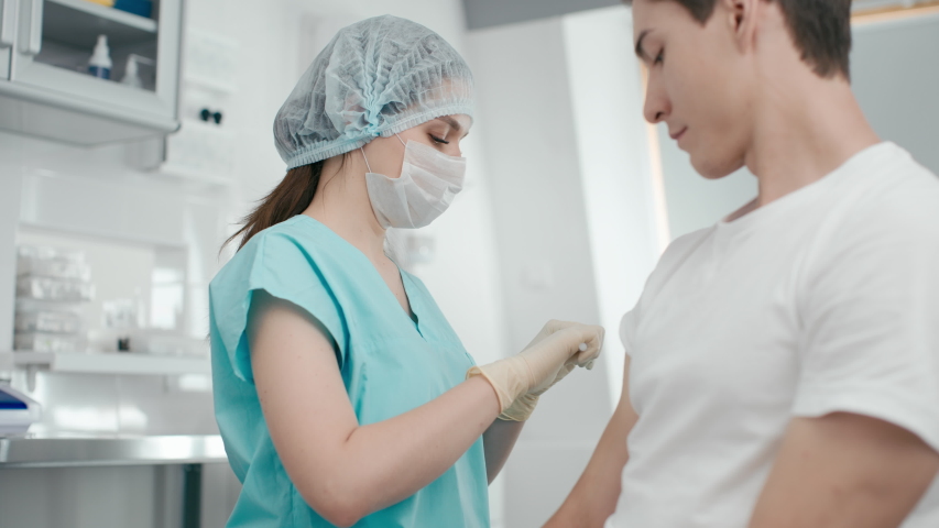 Hospital female employee at laboratory room. Inject corona virus vaccine in hand by medicine nurse indoors. Medical shot of biochemistry at coronavirus therapy at doctor office with science equipment Royalty-Free Stock Footage #1054685678