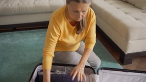 Tilt up medium shot of senior woman sitting on floor at home and packing suitcase for vacations. Female traveler putting on straw hat and day dreaming - Powered by Shutterstock - Get 15% off with code: PIKWIZARD15