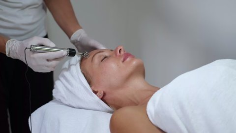 Cosmetology. Woman in clinic receiving stimulating electric facial treatment. Closeup Of Young Female Face During Microcurrent Therapy.  