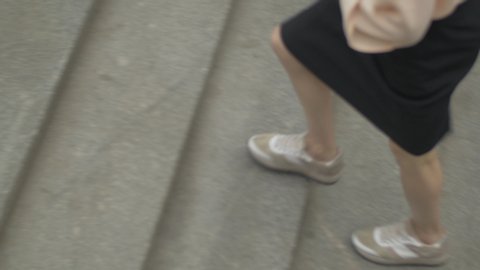 Close up of executive female legs wearing sneakers walking upstairs. Confident and independent woman going to work via subway in the city.