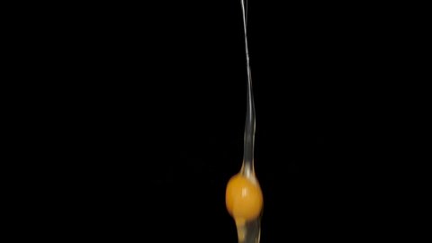 A broken chicken egg falls in slow motion. Footage shot on a black isolated background with artificial professional lighting 180fps.
