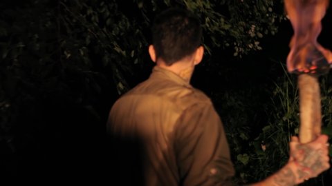 Boy in the woods at night with torch in hand, 4k footage