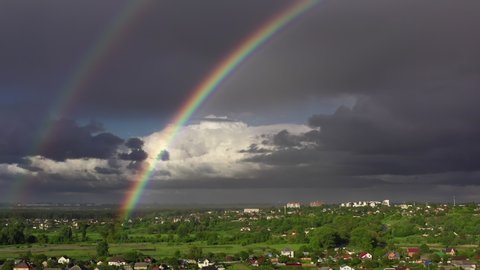 beautiful aerial drone panoramic view at double rainbow in gray rainy hard clouds at sky summer day, 4k. green countryside