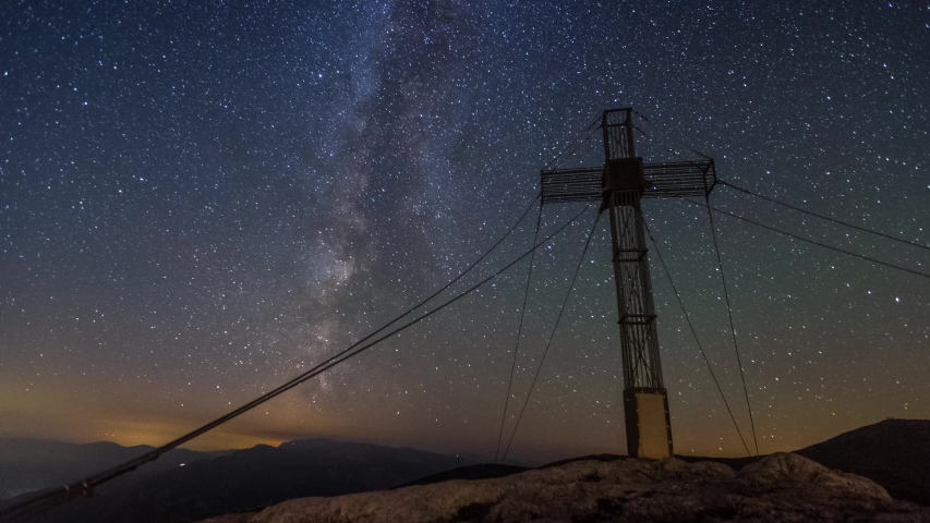 Milkyway moving in the Night with large Cross on the Mountain peak