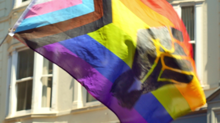 Progress pride flag with a black clenched raised fist in the middle waving and blowing during a BLM protest Royalty-Free Stock Footage #1054702508