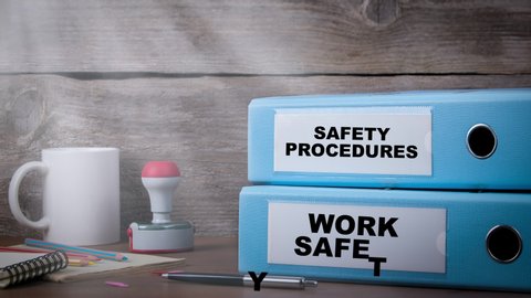Work Safety and Safety Procedures footage. Two light blue binders on the wooden desk in the office. Business background