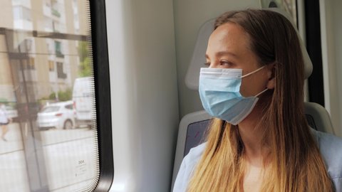 Coronavirus pandemic is over, quarantine end, young woman in protective medical face mask in a subway train using mobile. First tourists, open boarders, new reality after covid 19.