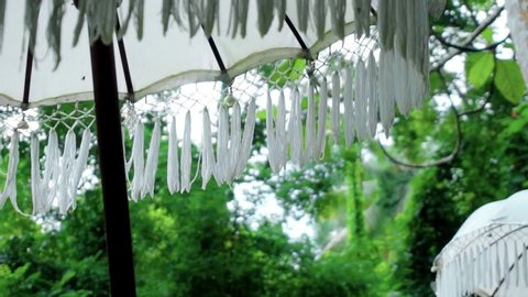 Video of an old white decorated fabric umbrella from the sun standing in the forest