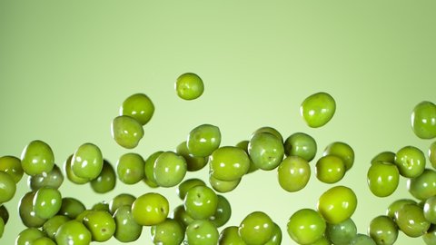 Super Slow Motion Shot of Flying Fresh Green Olives on Light Green Gradient Background at 1000 fps.