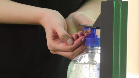 YOUNG GIRL WITH PAINTED NAILS ON HER HANDS USES AND PUTS ANTIBACTERIAL GEL TO WASH AND CLEAN BEFORE ENTERING A LOCAL BUSINESS