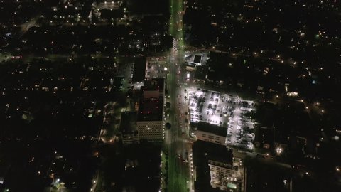 AERIAL: Lookup over Wilshire Boulevard Street in Hollywood Los Angeles at Night with View on Downtown and Glowing Streets and City Car Traffic Lights 