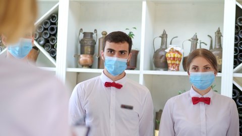 Employees of a restaurant in protective masks after quarantine. Interaction with restaurant manager and his staff on the terrace