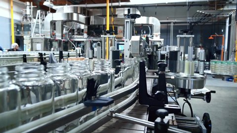 Beverage factory interior. Conveyor with glass bottles for juice or water. Modern equipment. Robotic automation line. packaging warehouse & processing facility.
