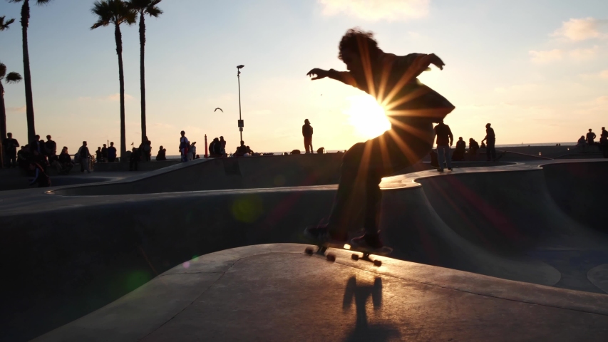 LOS ANGELES, CA, USA - JUNE 5, 2020: Skateboarder skateboarding trick in Venice Beach skate park at sunset, Los Angeles. Concept of healthy millennial active lifestyle, skateboarding & summer travel 