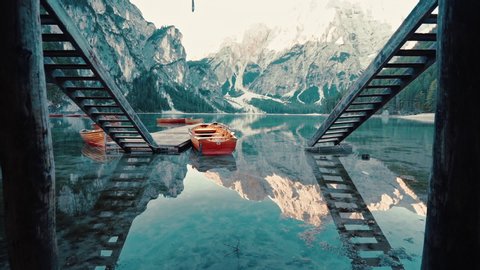 Passing slowly between twin stairs leading to the glass like reflections on Lake Braies, Italy, slow motion